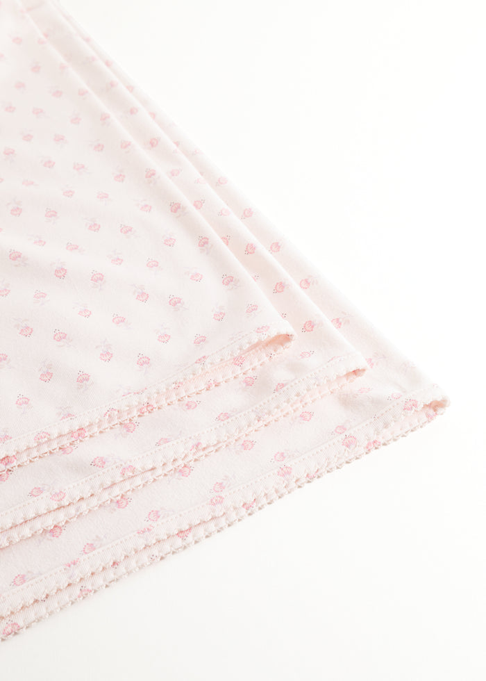 Mini rug with small pink flowers and a wavy edge.