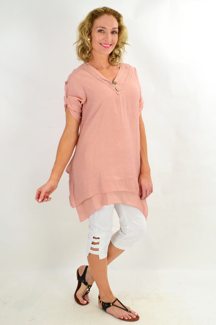 Blush coconut-colored La Mode short sleeve tunic top with button details, displayed on a hanger.