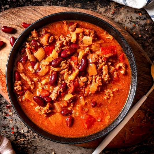 Hearty chili with ground meat, kidney beans, onions, and peppers in a rustic bowl, ready to eat.