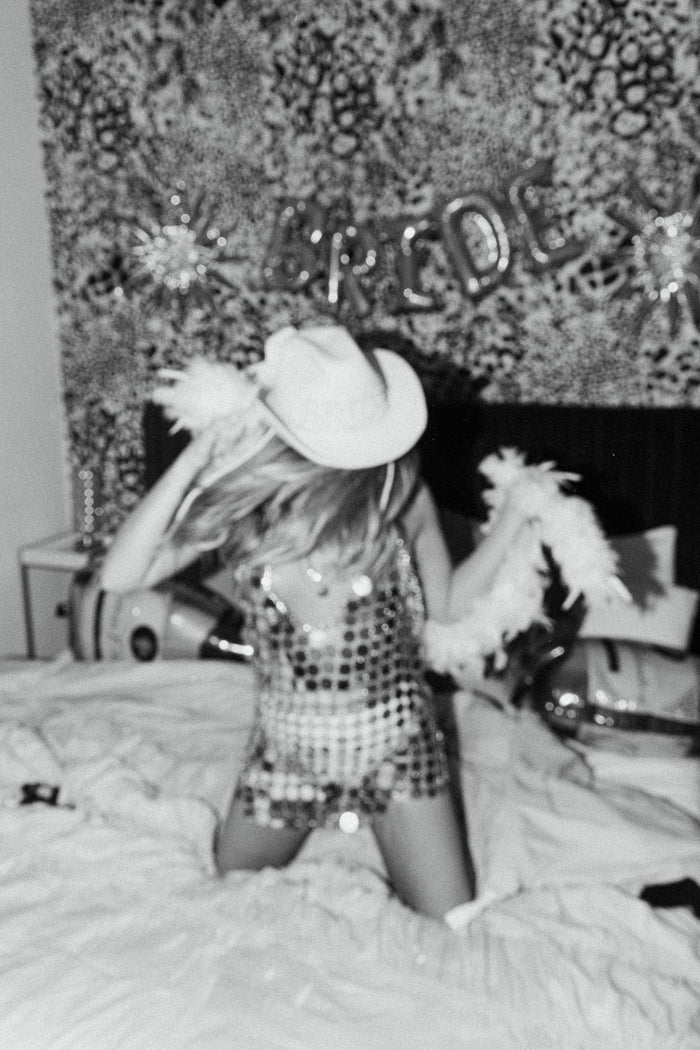 Sequin disco mini dress worn with cowboy hat and feather boa at a bachelorette party.