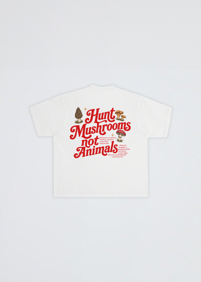 A white short-sleeve T-shirt laid flat against a light gray background, featuring a large red graphic text print that reads 'Hunt mushrooms not animals' with small mushroom illustrations.