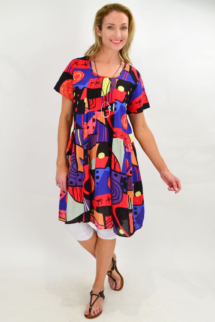 Hourglass Ken Done Inspired Peasant Tunic Dress with colorful floral patterns and relaxed fit, displayed on a hanger.