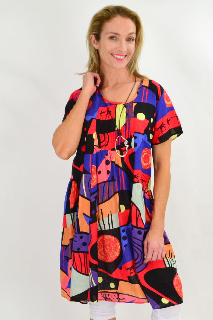 Hourglass Ken Done Inspired Peasant Tunic Dress displayed on a hanger, featuring colorful patterns and a relaxed, bohemian style.