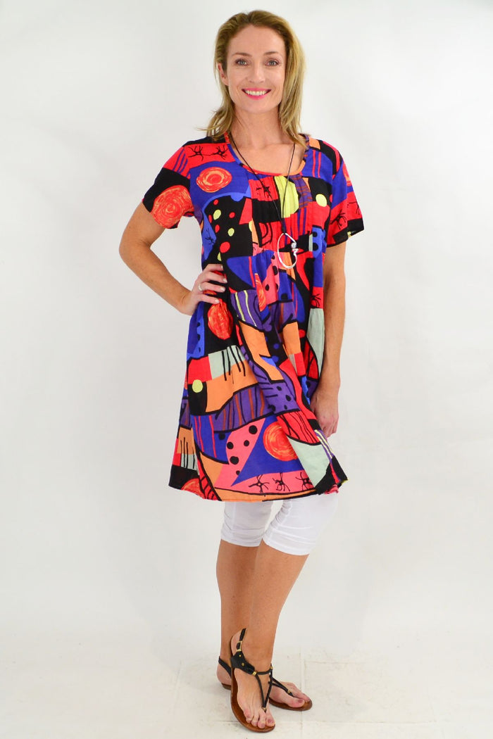 Ken Done inspired peasant tunic dress by Hourglass with floral pattern and relaxed fit, shown on a hanger.