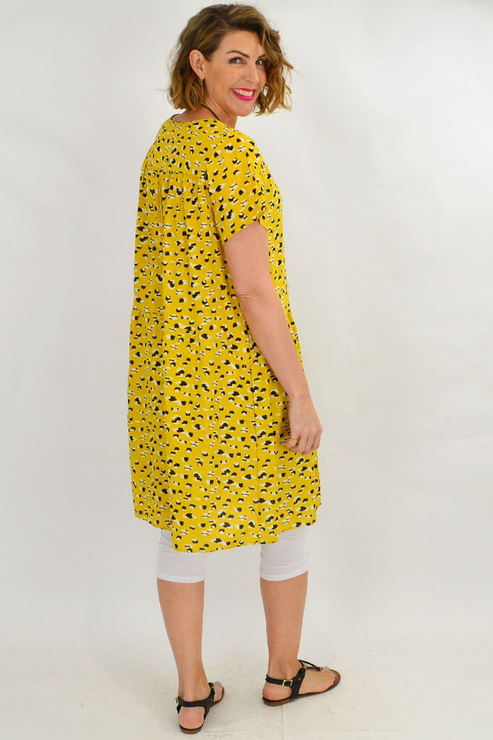 Mustard peasant tunic dress by Hourglass featuring loose fit, long sleeves, and bohemian style, shown on a hanger.