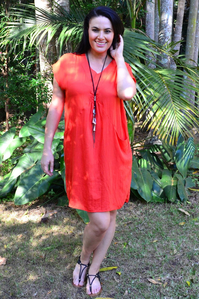 Orange Willow Tunic Dress by Willow Tree displayed on a hanger, showcasing its flowy fabric and vibrant color.