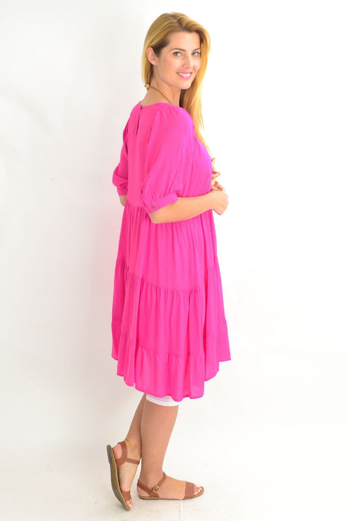 Pink Willow Tree tiered tunic dress with flowing fabric and layered design, displayed on a hanger against a neutral background.