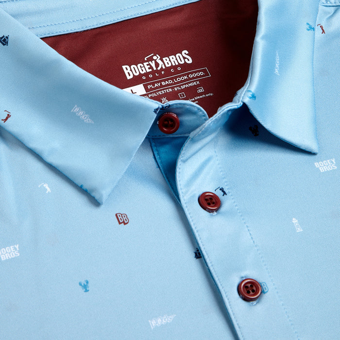Close-up of the Port - Polo in light blue with an athletic fit, maroon inner collar, maroon buttons, and golf-themed icons plus “BB” logos printed on the fabric. Size and brand label are visible inside the collar.