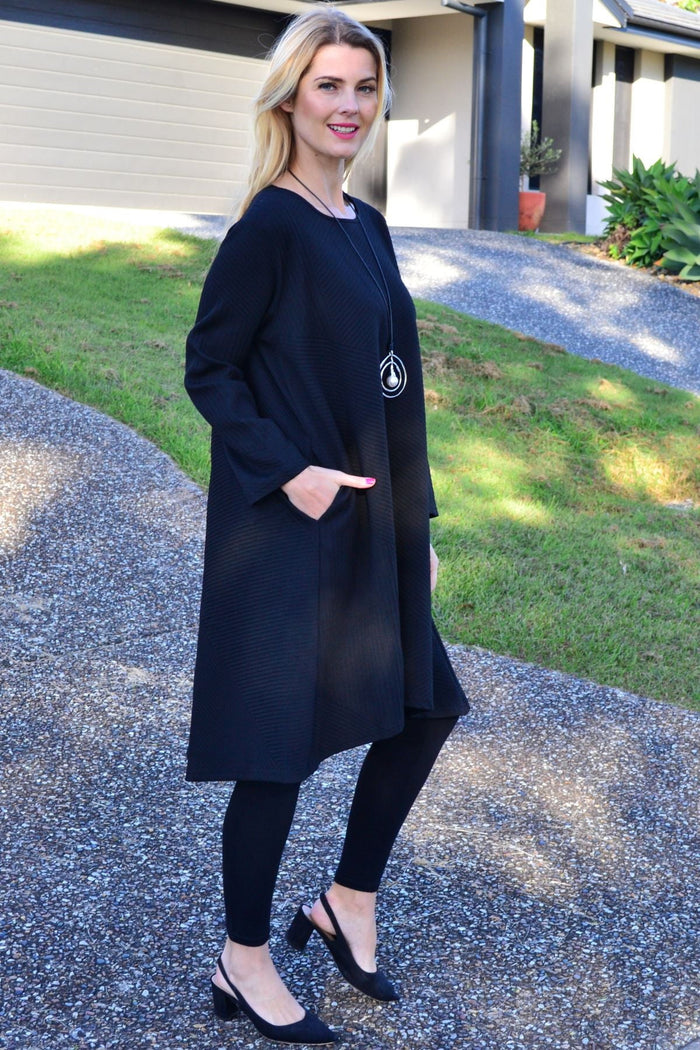 Relaxed black textured tunic dress by Poney, featuring a loose fit and stylish fabric detail, displayed on a hanger.