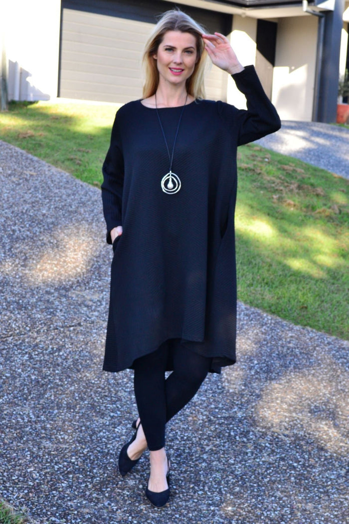 Black textured tunic dress from Poney featuring a relaxed fit and stylish design, displayed on a hanger.