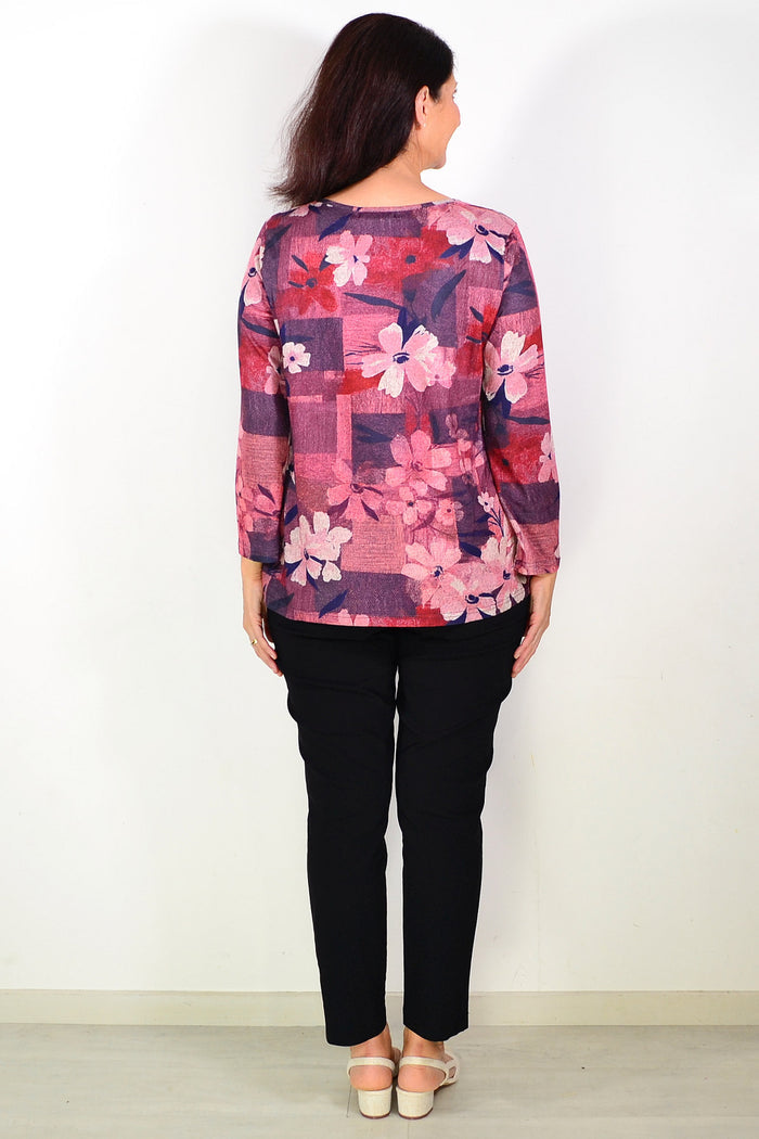 Salmon pink floral print tunic top by Hourglass with long sleeves and relaxed fit, shown on a hanger.
