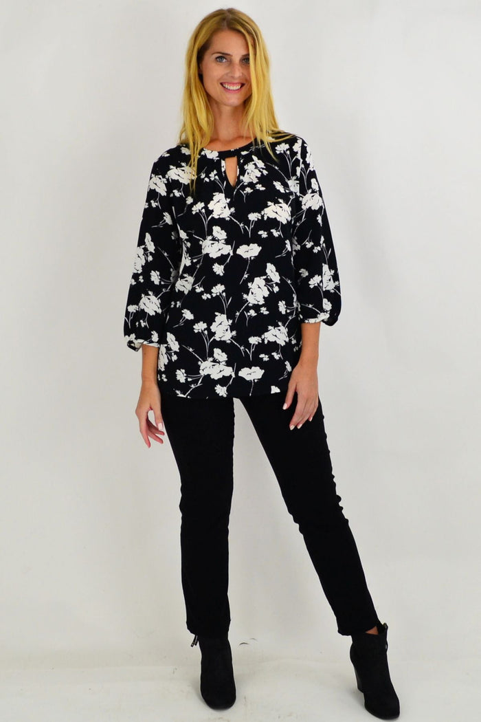 White flower print Envogo Whitney tunic displayed on a hanger, showcasing its flowy fabric and floral design.