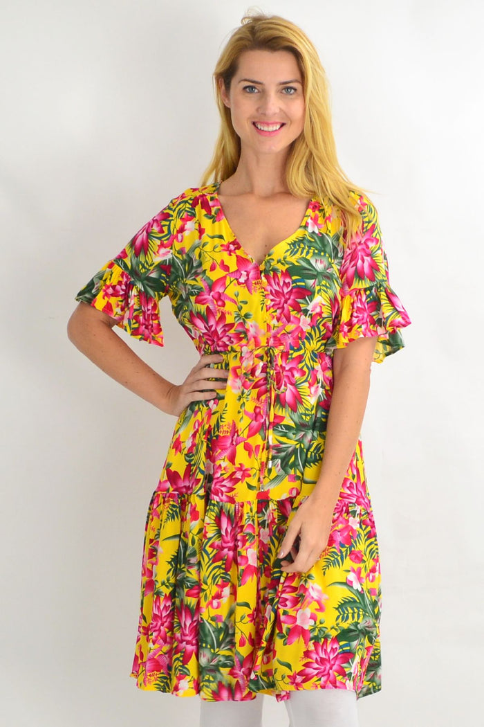 Yellow frilly orchid tunic dress by Willow Tree with pink floral pattern, displayed on a hanger.