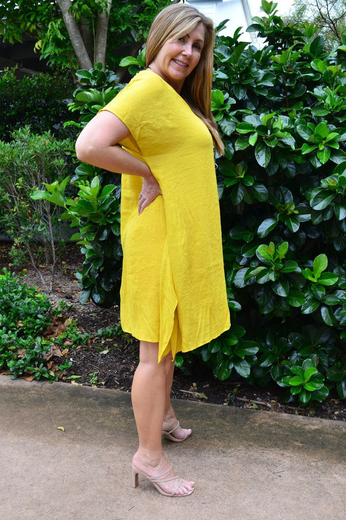Yellow Wishstone oversized drop shoulder tunic dress hanging on a wooden hanger with a simple background.
